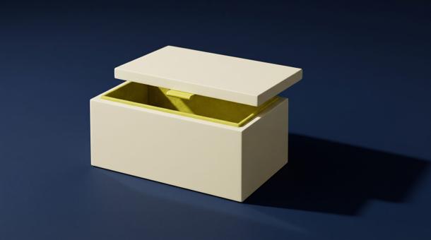 A cream lacquered box with its lid lifted clear and tilted, revealing an acid yellow-green lining, on a smooth navy surface.