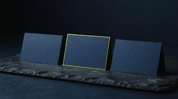 Three navy cards standing upright in a row on slate, the centre one slightly taller with a chartreuse edge.