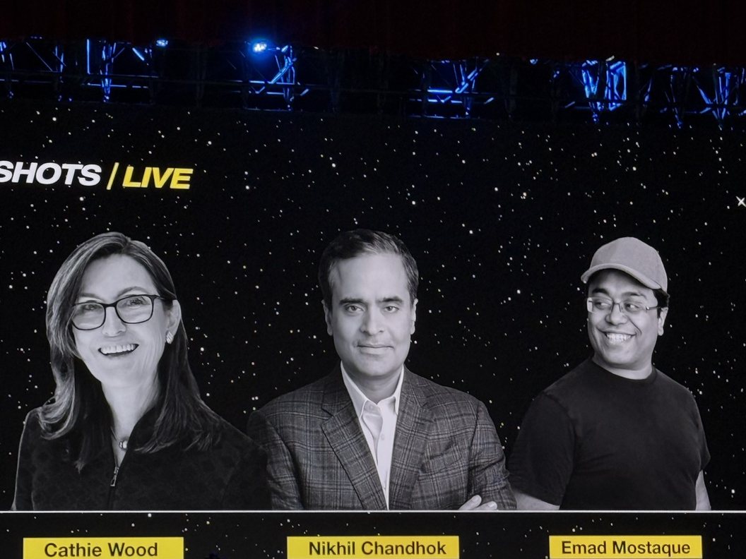 The big screen at Moonshots Live showing the afternoon panel's title card: Cathie Wood, Nikhil Chandhok and Emad Mostaque